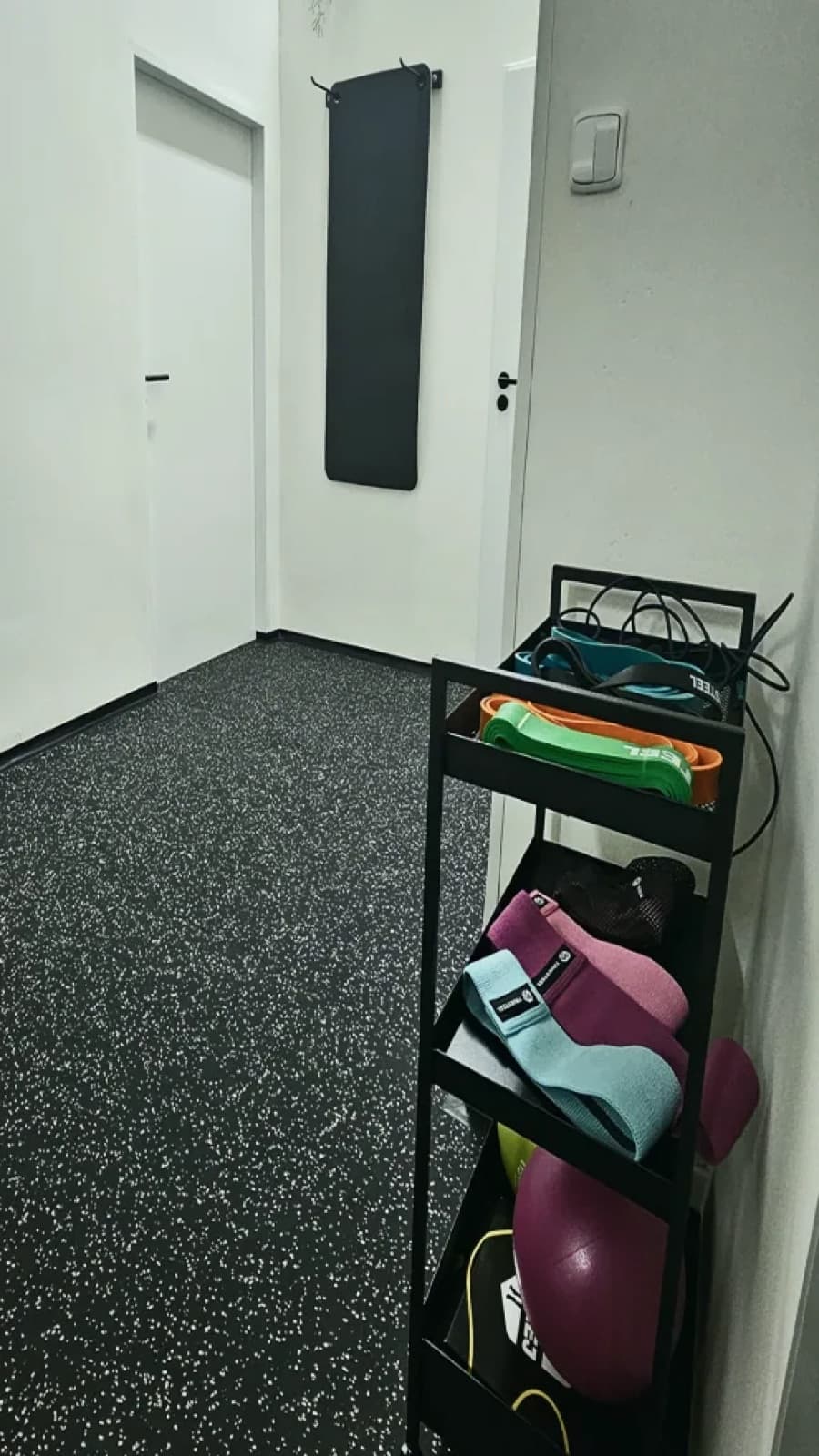 Stojan s odporovými gumami, podložkami a míči v posilovně The Jungle